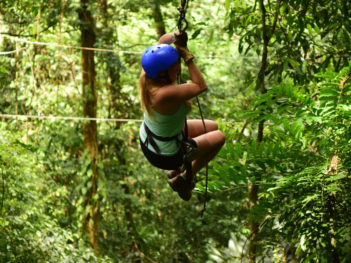 Viajera en la tirolesa entre los árboles de la selva